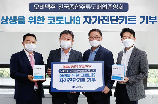 오비맥주가 코로나19 극복을 위해 전국종합주류도매업중앙회와 함께 자가진단키트를 기부하는 모습