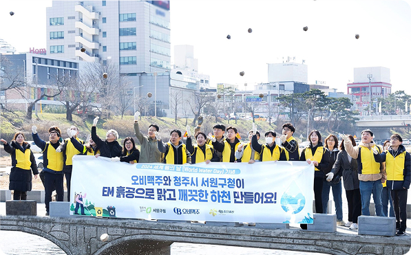 오비맥주와 청주시 서원구청이 EM 흙공을 던지며 하천 정화 활동을 진행하는 모습