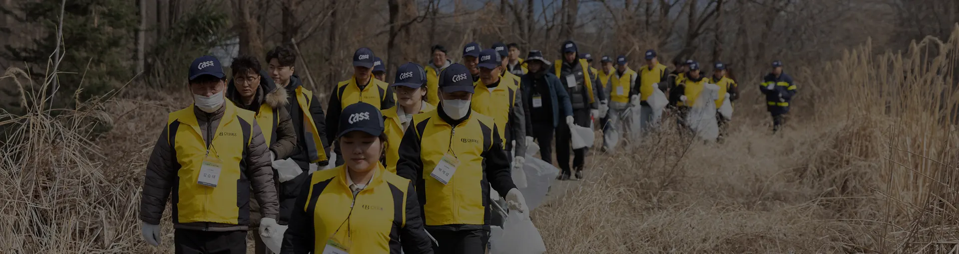 오비맥주 임직원들이 하천 주변을 걸으며 쓰레기를 수거하는 환경 정화 봉사활동 모습입니다.