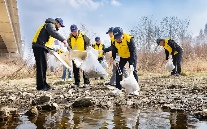 오비맥주 임직원들이 하천 주변에서 쓰레기를 수거하는 환경 정화 봉사활동 모습입니다.